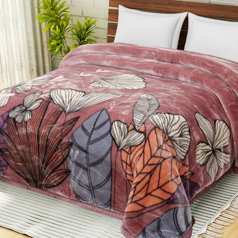 A double bed with a multicolored floral blanket spread over it, with a pink, orange, and gray color scheme.