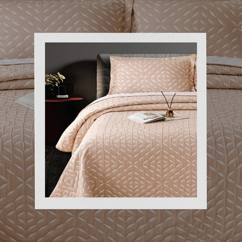 A bed covered with a multicolor jacquard bedcover set, with two pillow covers placed on it, against a neutral background.