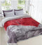 A double bed blanket with a minky texture in gray and red colors, displayed on a bed in a room with a window and decorative pillows.