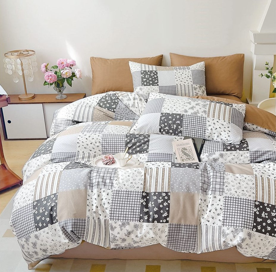 A king-size bed with a printed bed sheet set and two pillow covers, featuring a mix of gray, beige, and white geometric patterns.