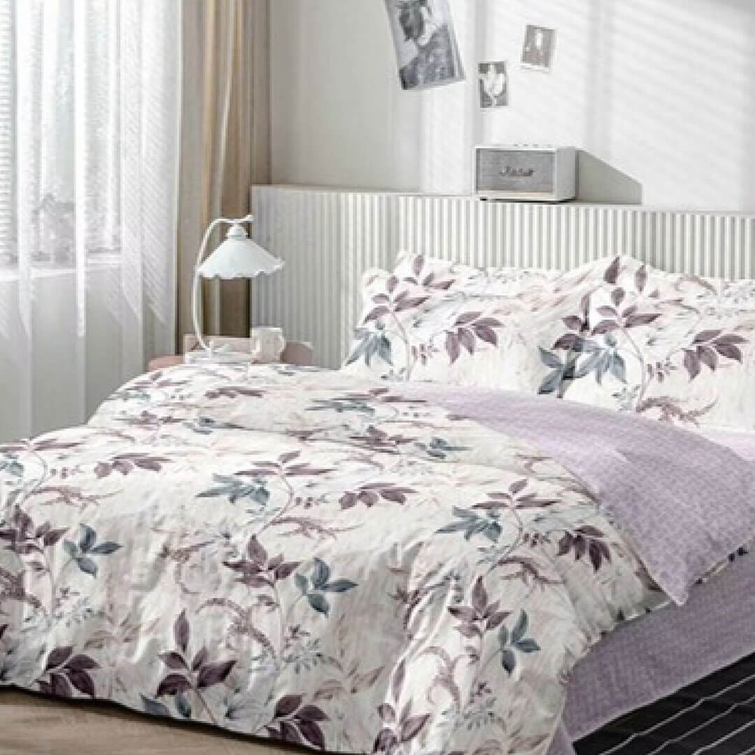 Bed with floral duvet cover and pillows in a bedroom setting.